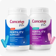 Conceive Plus Fertility Support Him & Her Bundle featuring two supplement bottles on a white background. The Men’s Fertility Support bottle is on the left with two turquoise capsules near the lower left, and the Women’s Fertility Support bottle is on the right with two pink capsules near the lower right, representing a complete couple’s fertility support solution.