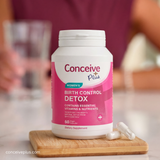 Conceive Plus birth control detox supplement bottle on a wooden cutting board with blurred background