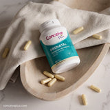 Conceive Plus prenatal supplement bottle with capsules on a wooden plate and fabric background